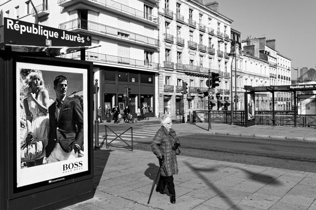 Photo de rue, deux personnage d'une publicité observent un passante avec une canne
